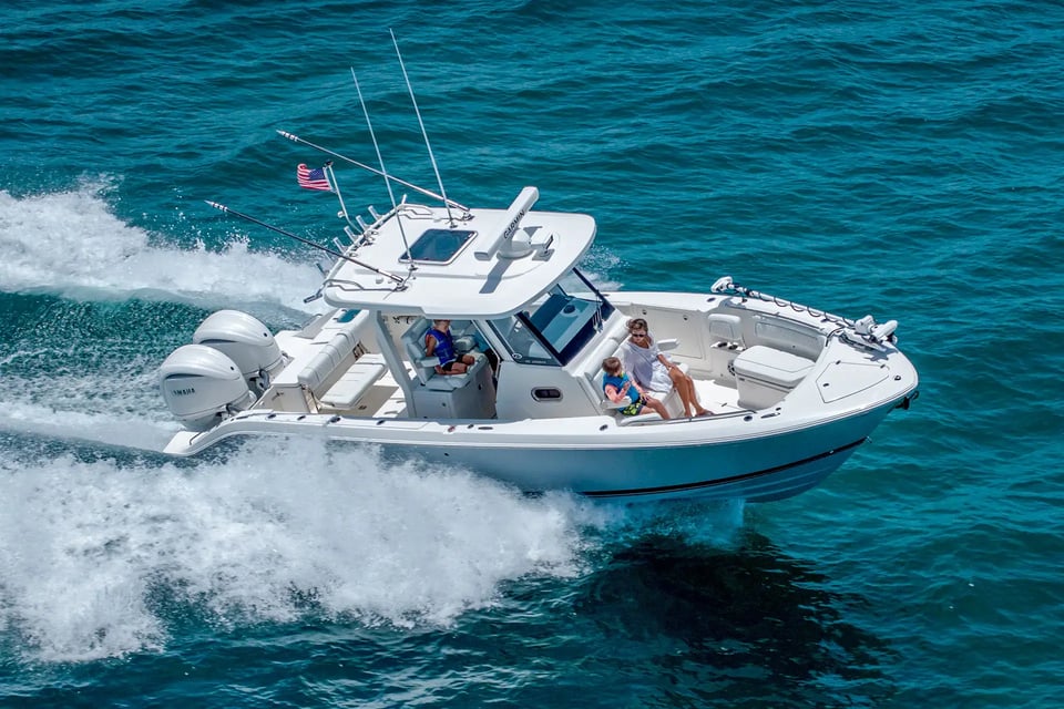 Pursuit S 288 30-foot center console boat powered by twin Yamaha outboards cruising offshore with a family onboard.