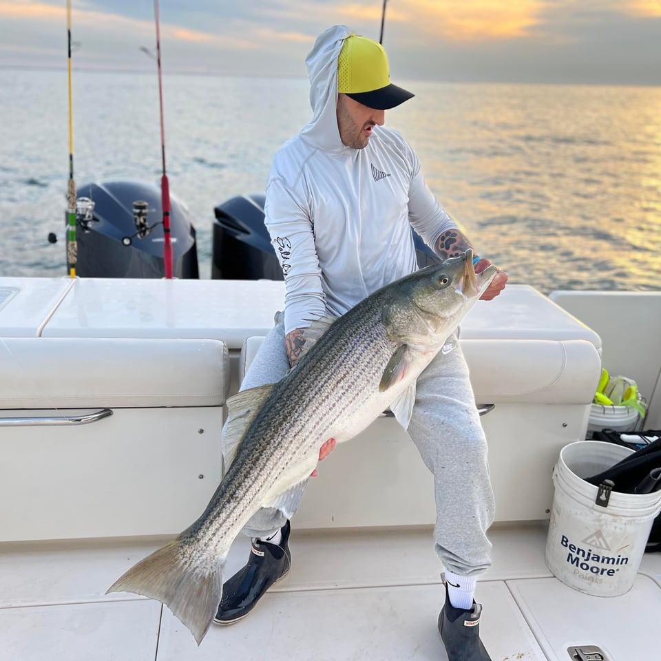 Brandon Weitz holds a striped bass he caught on his Pursuit Boat