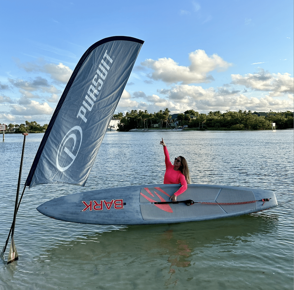 Liubov with paddleboard and Pursuit flag. 