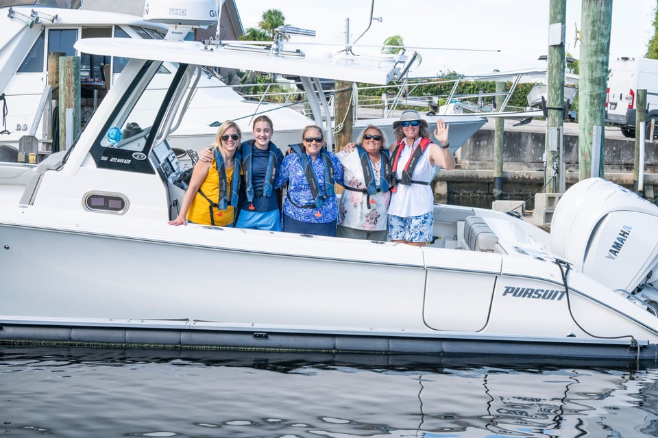 A group of ladies pose on a Pursuit S 288 after taking Chapman Course for boat safety.
