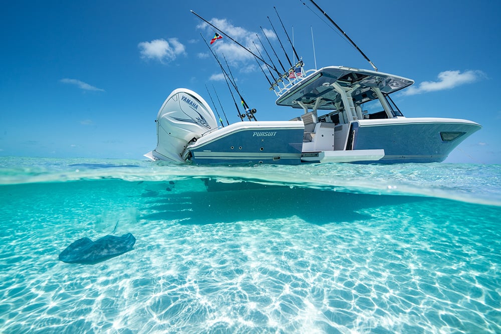 Pursuit Boats S 428 fishing and cruising center console sport boat with beach door open and quad Yamaha Engines in the clear water of the Bahamas.